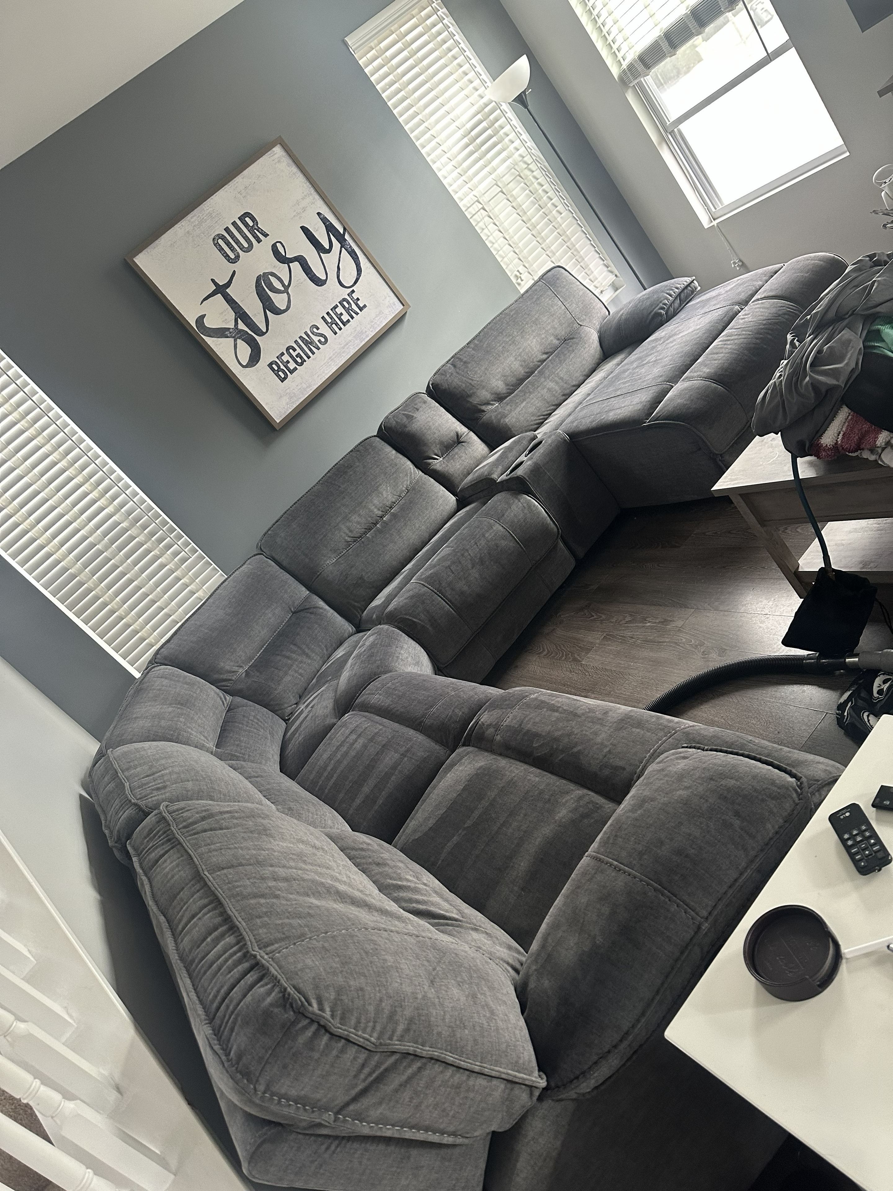 Gray sectional sofa cleaned by EZ Breezy — 'Our Story Begins Here' sign in background